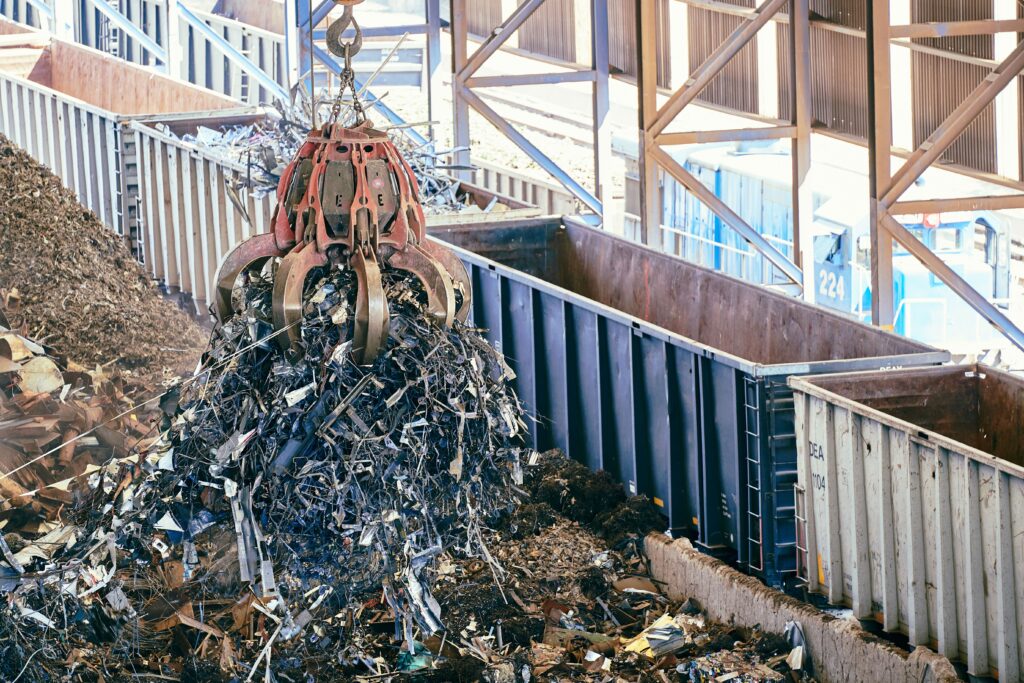An industrial claw crane lifts metal scrap in a recycling facility, showcasing efficient waste management.