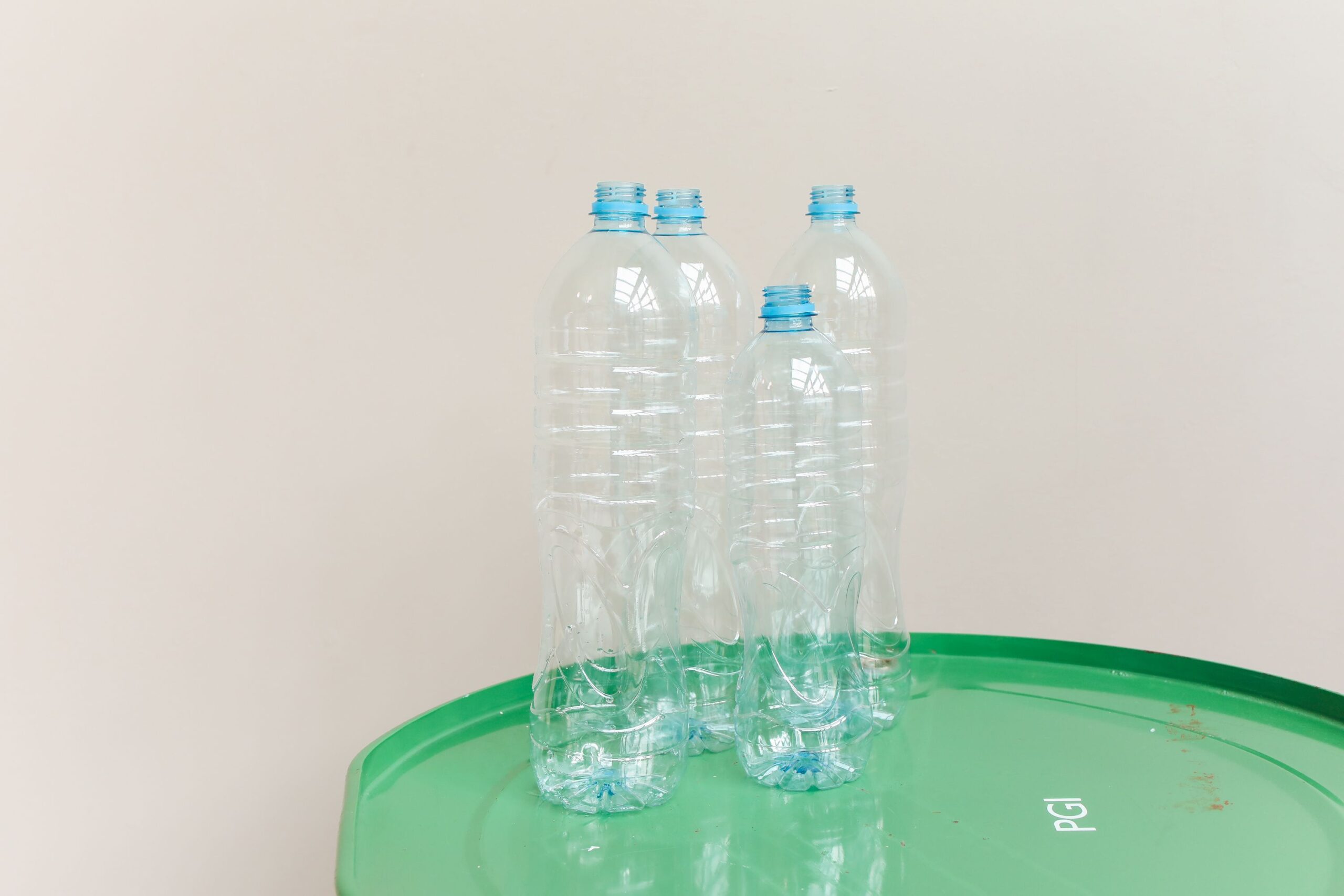 Clear plastic bottles standing on a green drum, emphasizing recycling and sustainability.